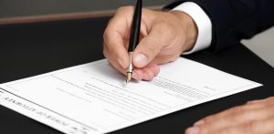 zoomed-in image of close-up of a hand signing legal documents