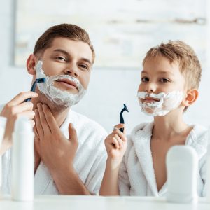 a man showing a boy how to shave